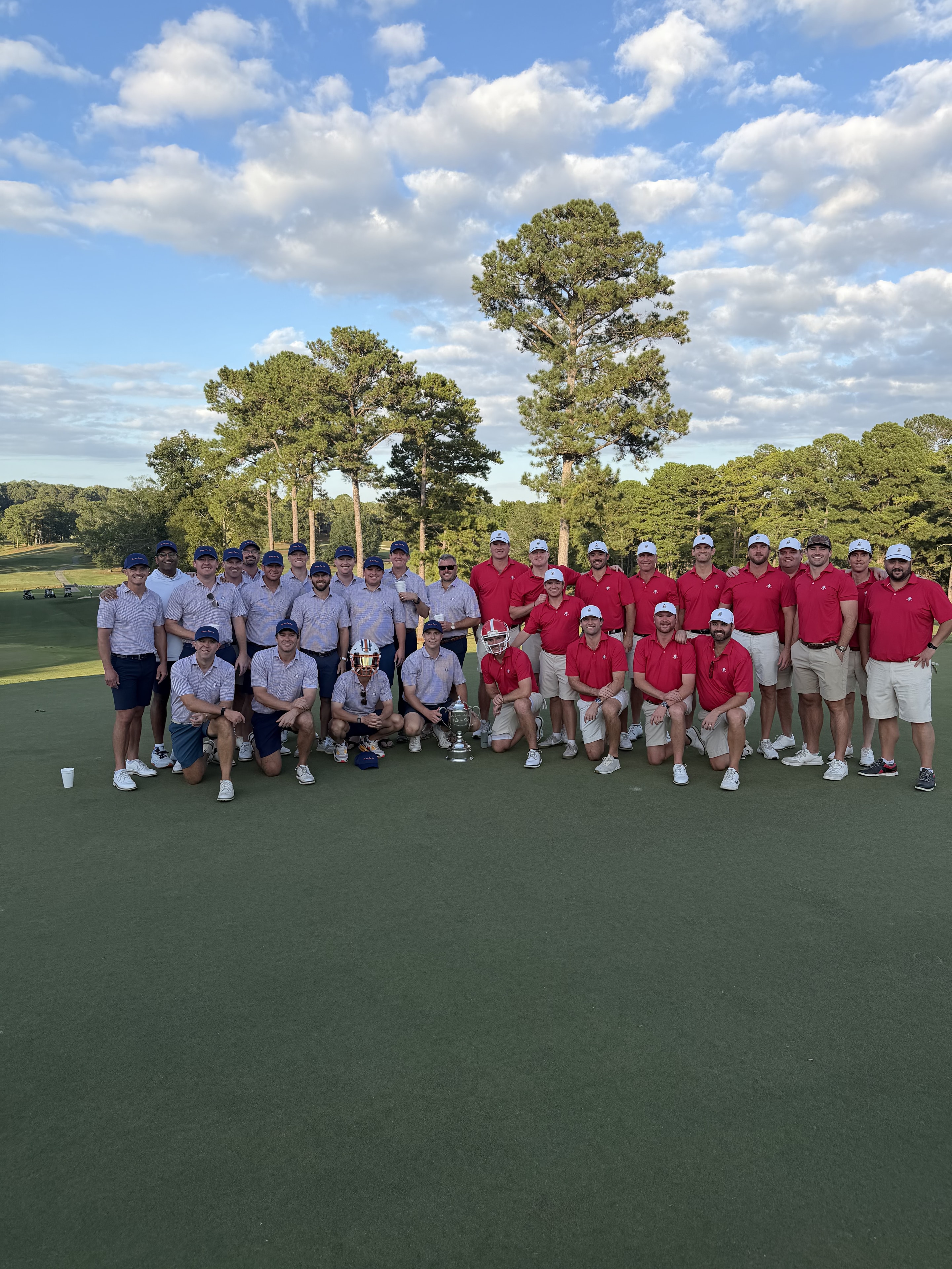 Both teams posed together on the green with the Cup and helmets, 2025