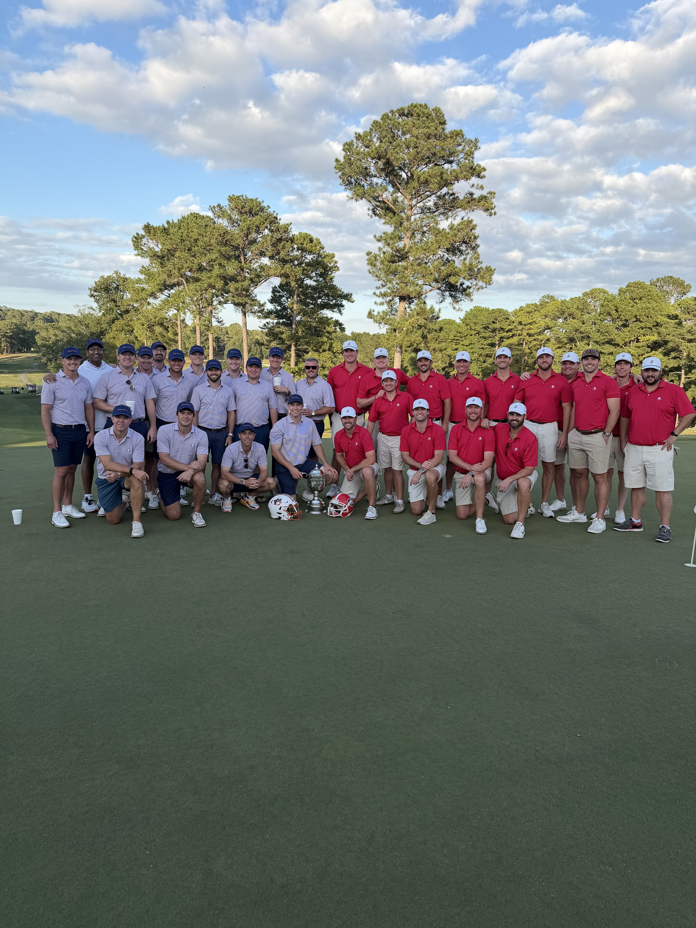 Both teams posed together on the green with the Cup and helmets, 2025