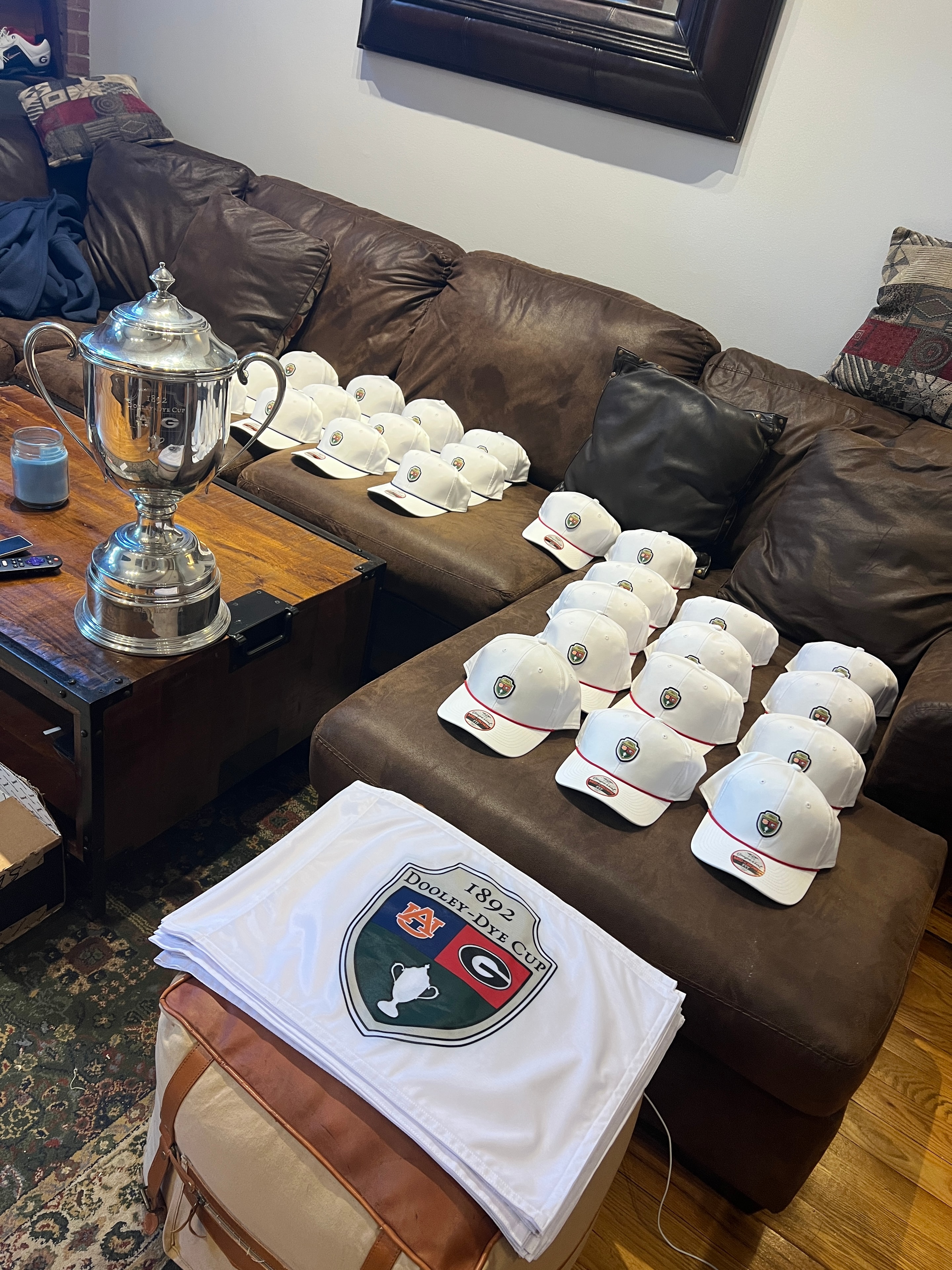 Dooley-Dye Cup caps and flag laid out in a living room before the tournament