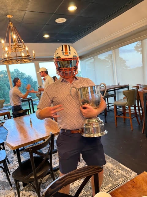 Player wearing an Auburn helmet and holding the Dooley-Dye Cup indoors