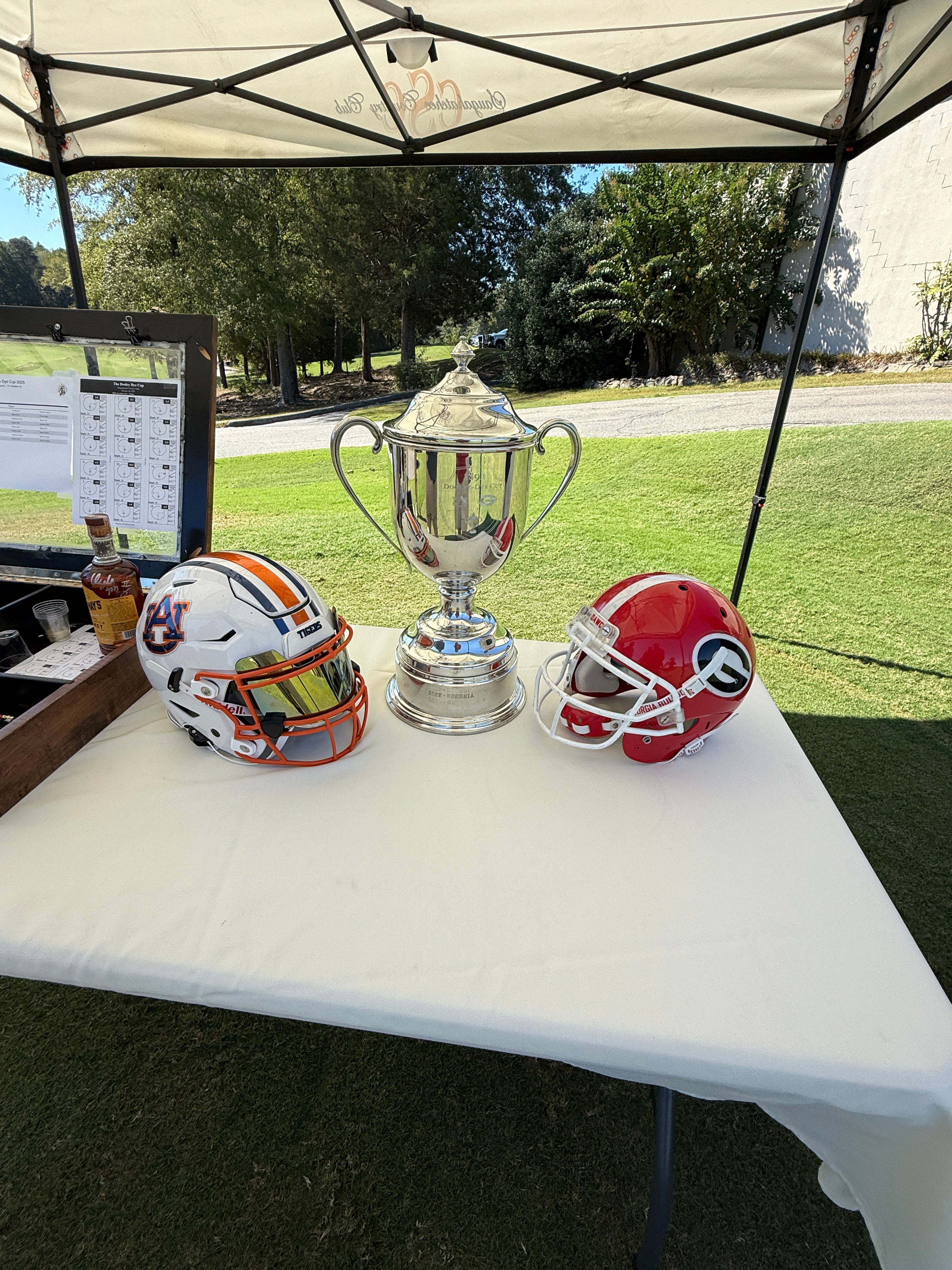 Auburn and Georgia helmets with the Cup on a table at the tournament tent