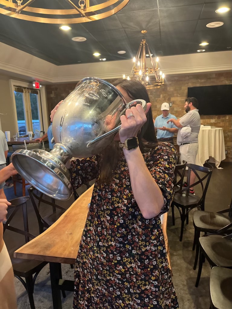 Woman drinking from the Dooley-Dye Cup trophy at the post-round dinner