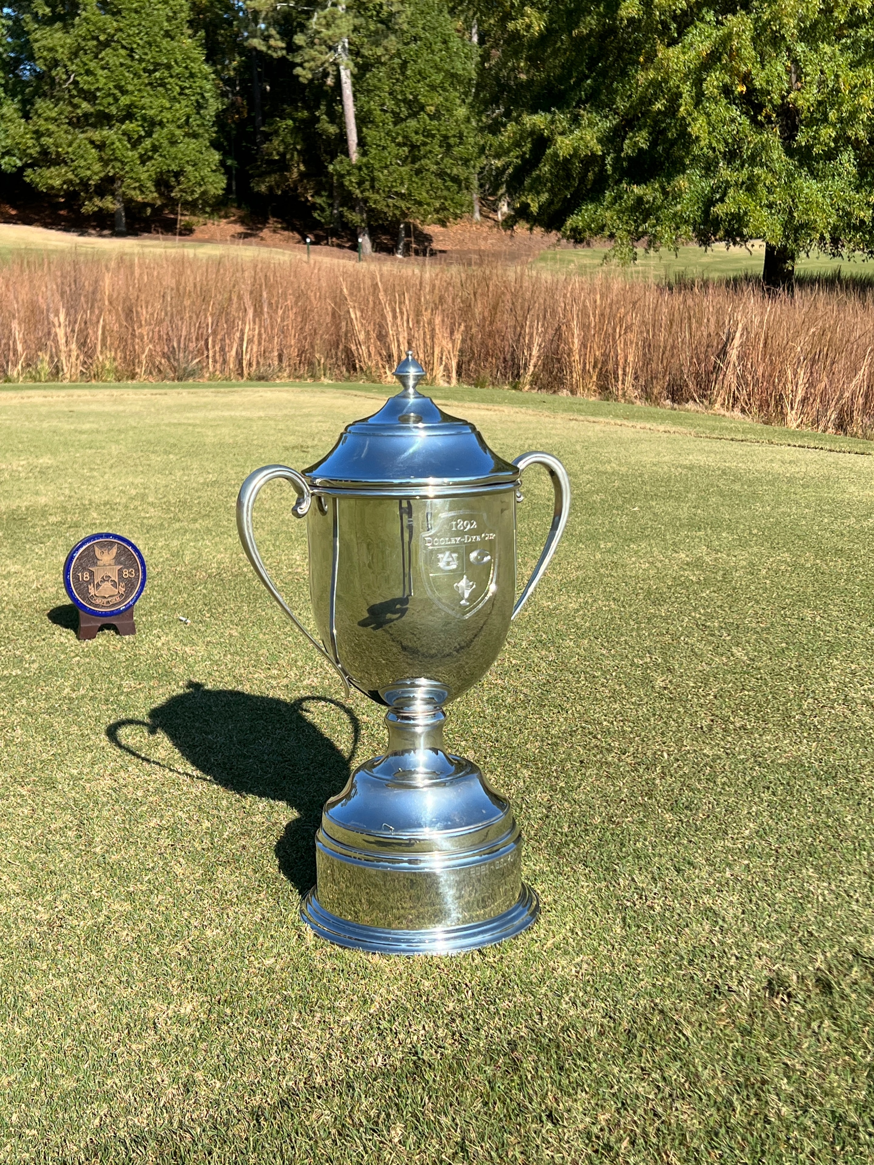 The Dooley-Dye Cup trophy lying on the fairway grass