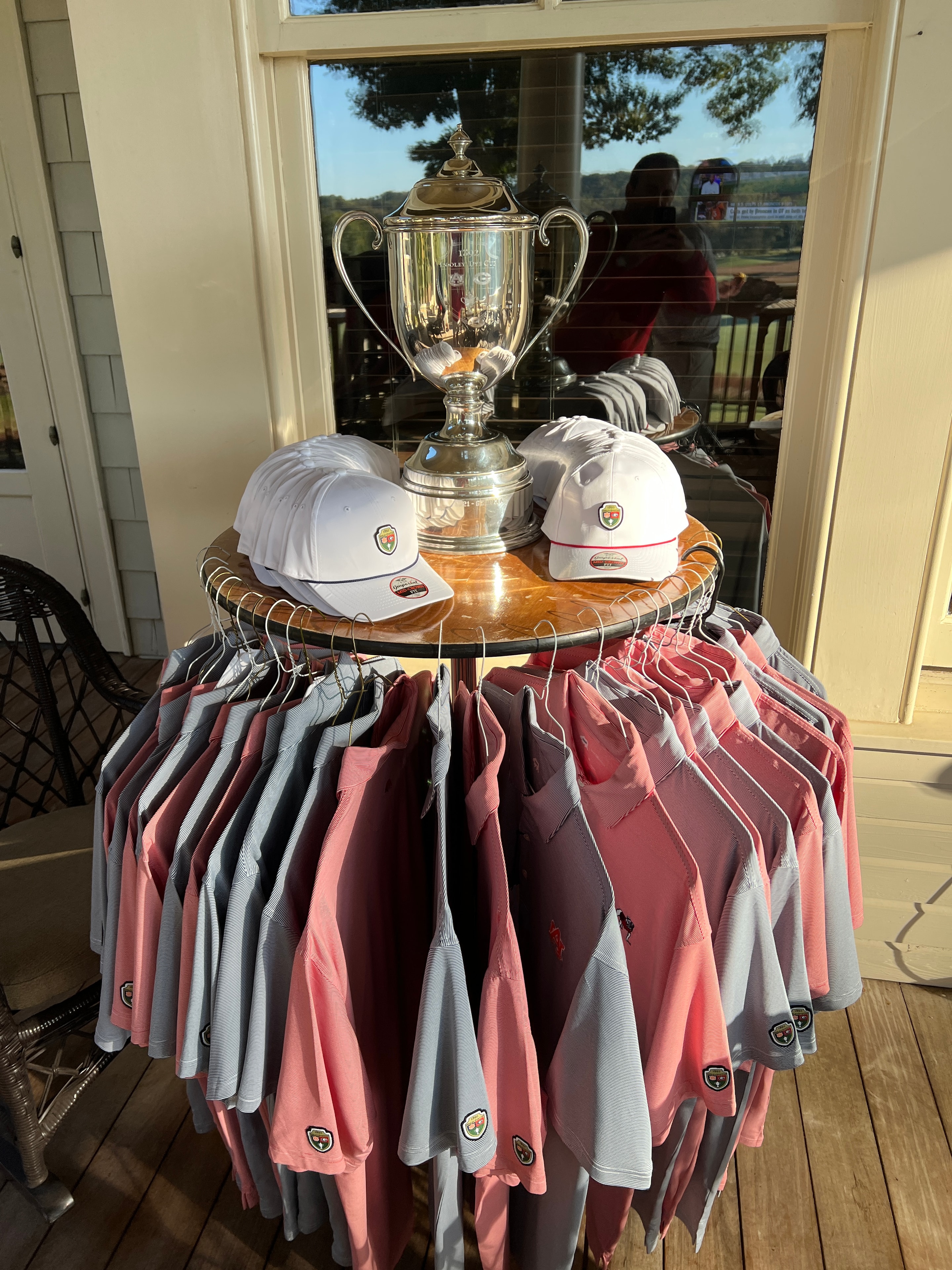 Trophy displayed alongside tournament polos and caps in the pro shop