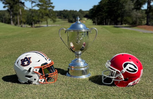 Auburn and Georgia helmets flanking the Dooley-Dye Cup trophy on the fairway
